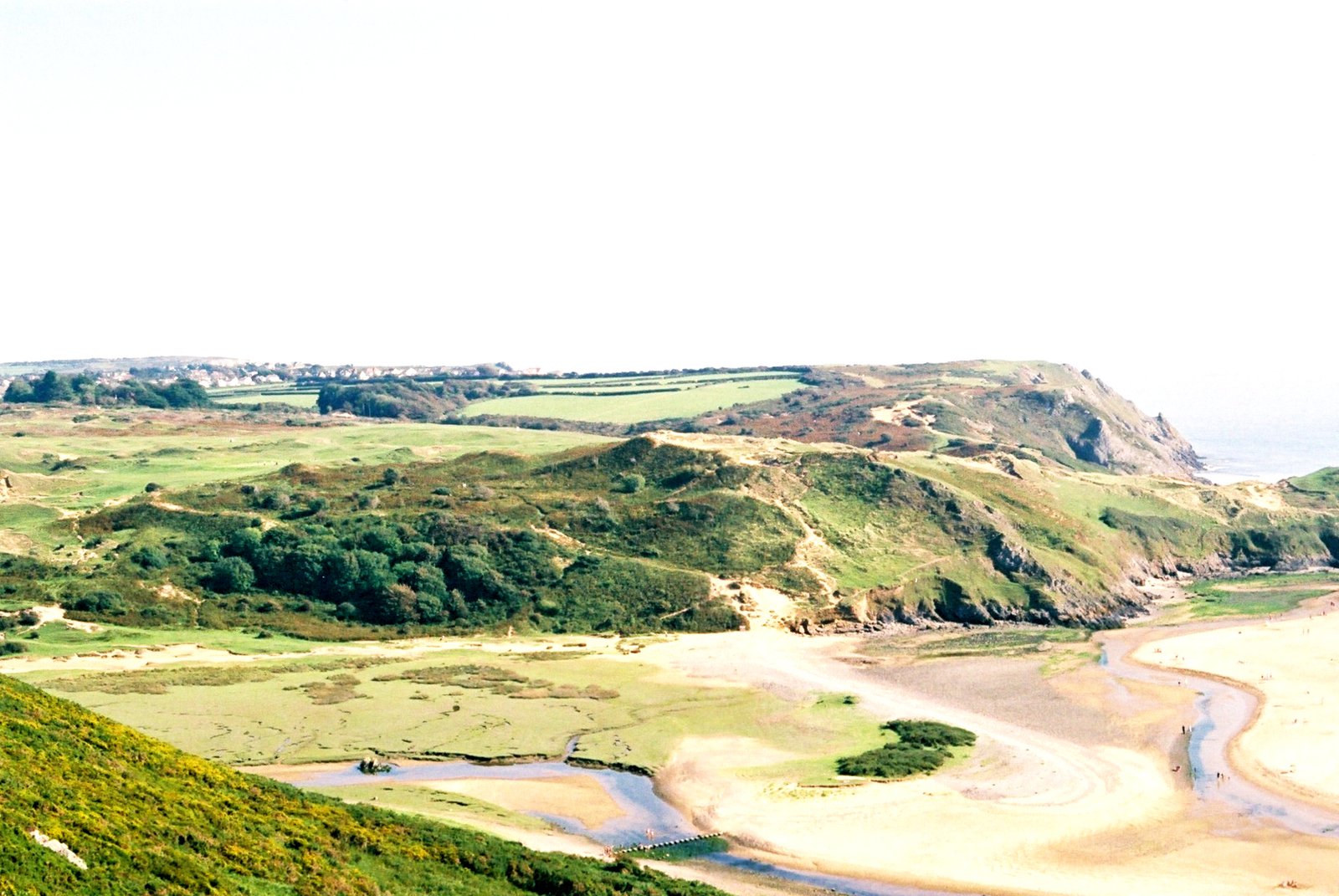 a view looking down on an empty river and grassy hills