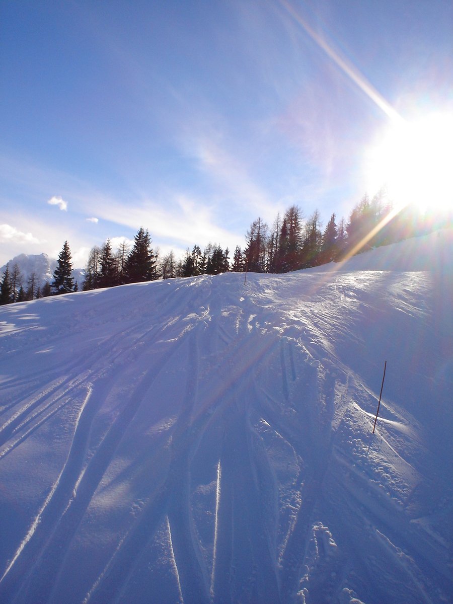 the sun is shining on the snowy slopes