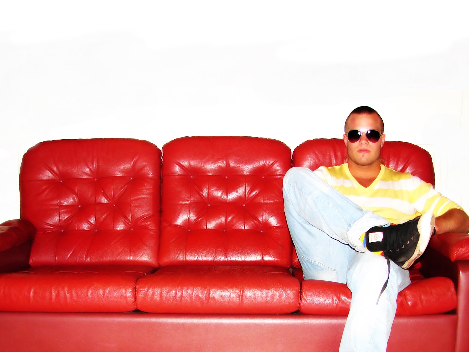 a man sitting on top of a red leather couch