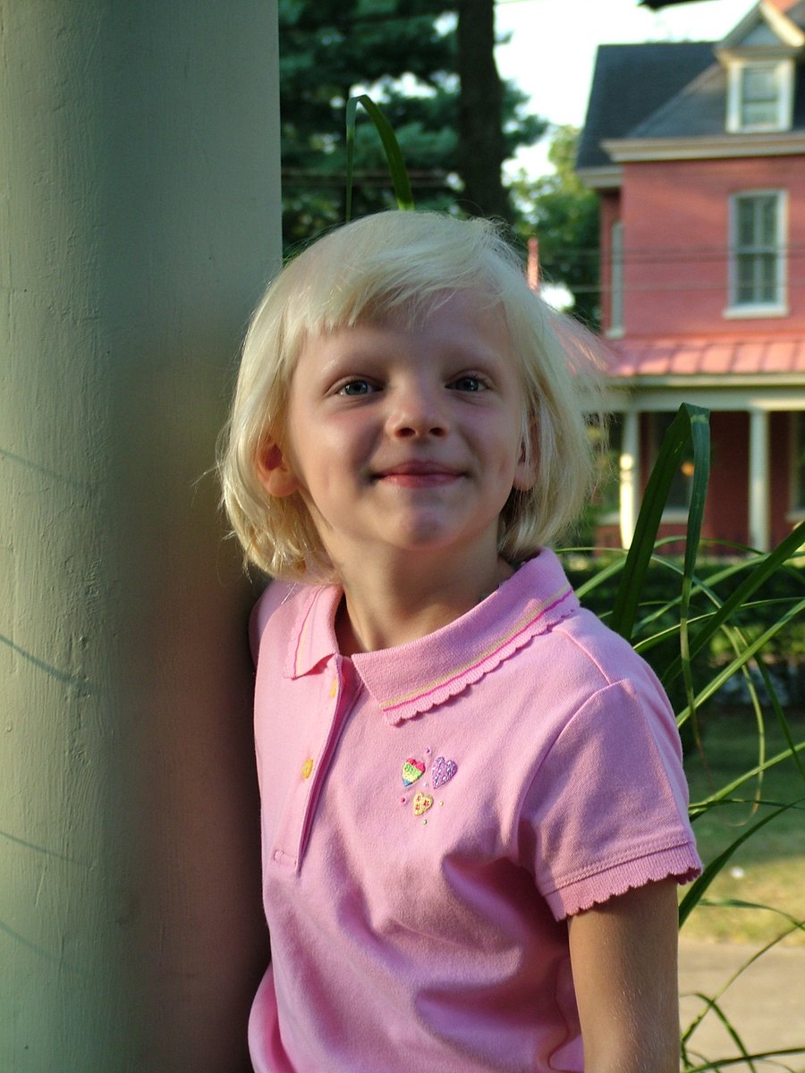 a  wearing a pink top stands next to a tree