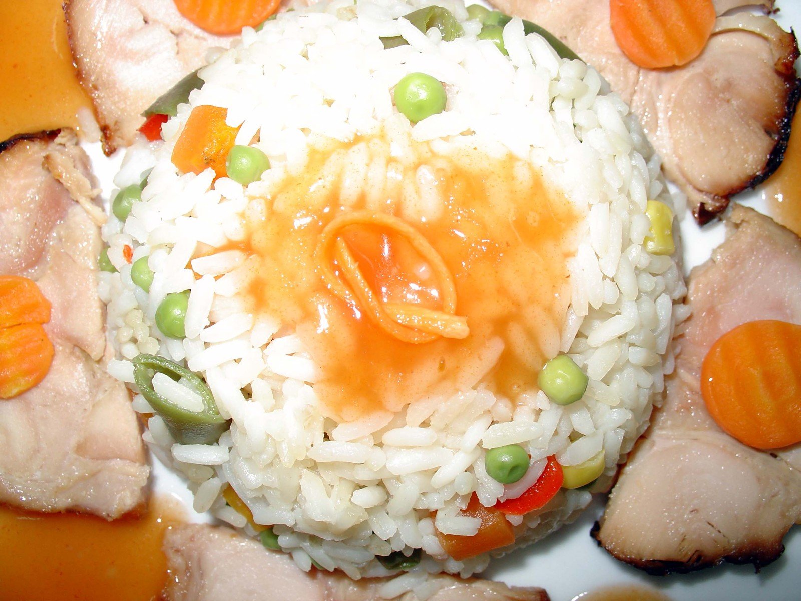 a plate with rice, carrots, peas, and meat on it