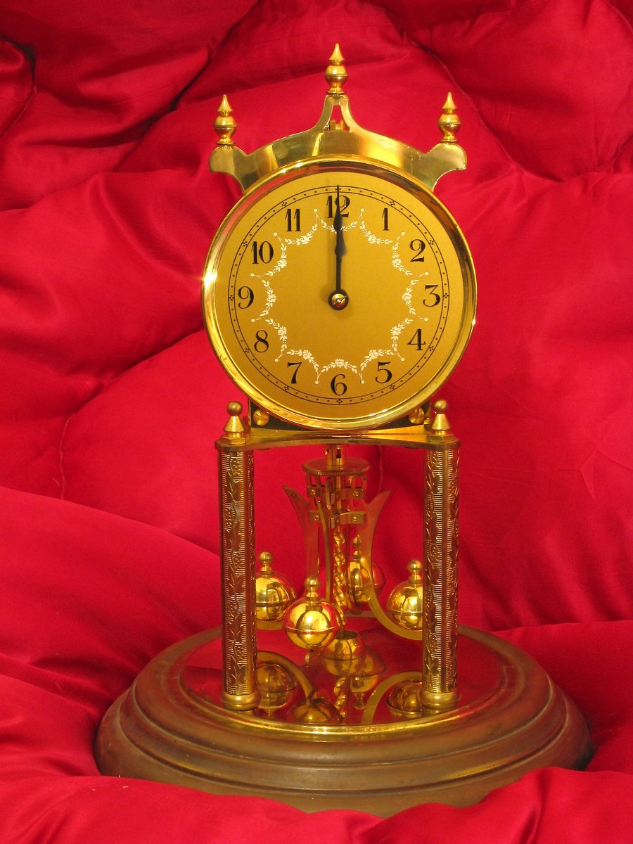 an ornately decorated gold clock sitting on red cloth