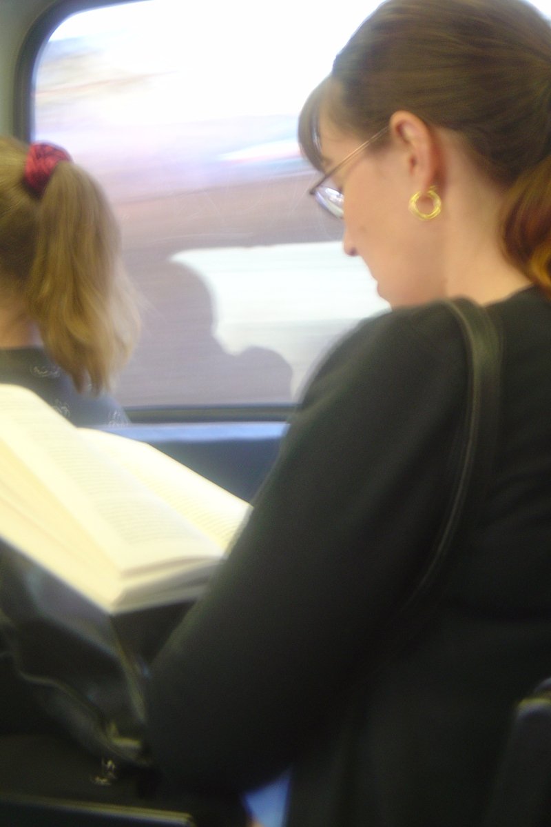 a woman holding an open book on the side of a train