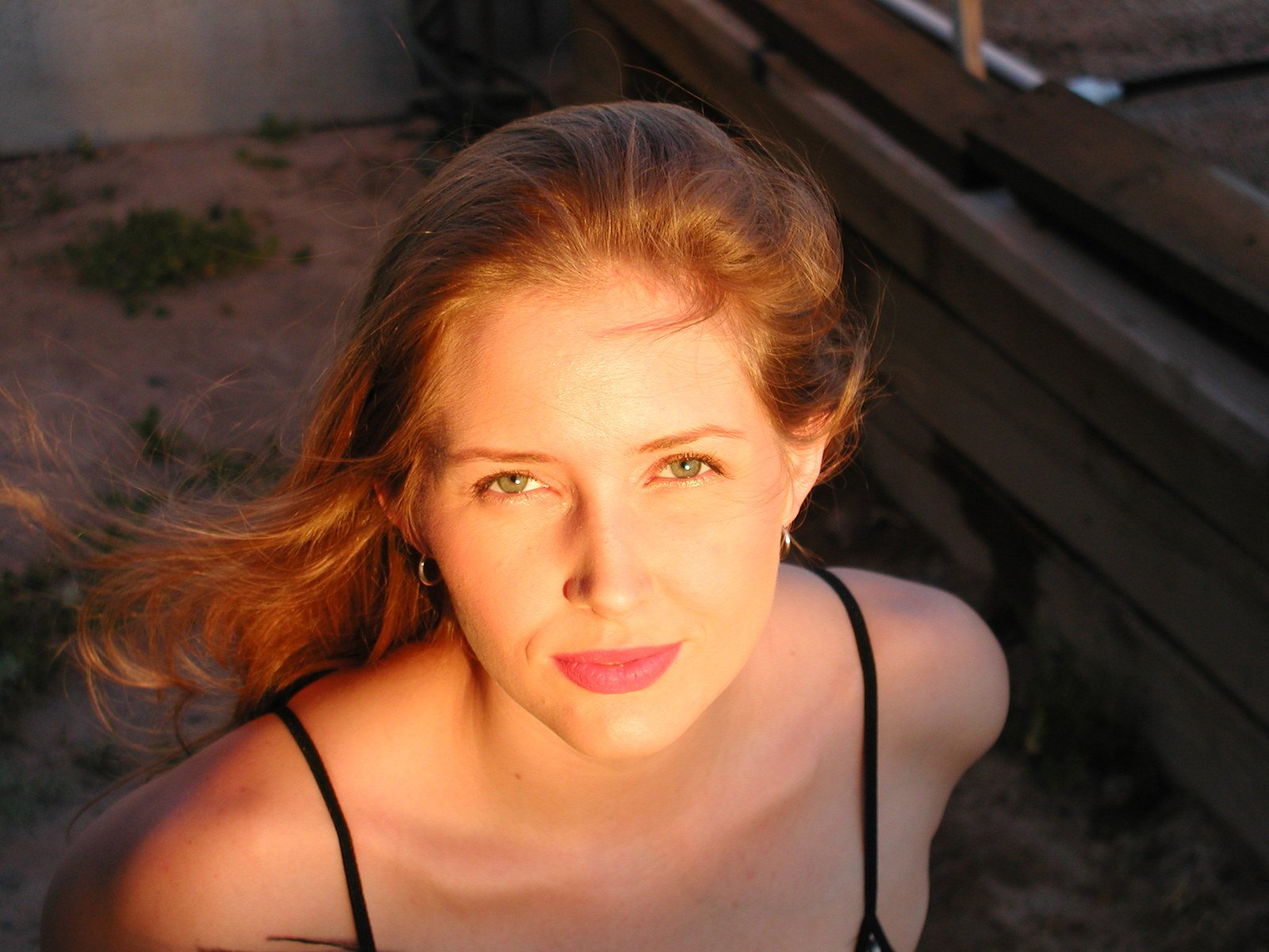 a woman sitting on a bench next to a wooden fence