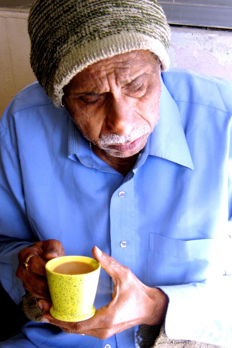 a man is holding up a mug while looking down at his thumb