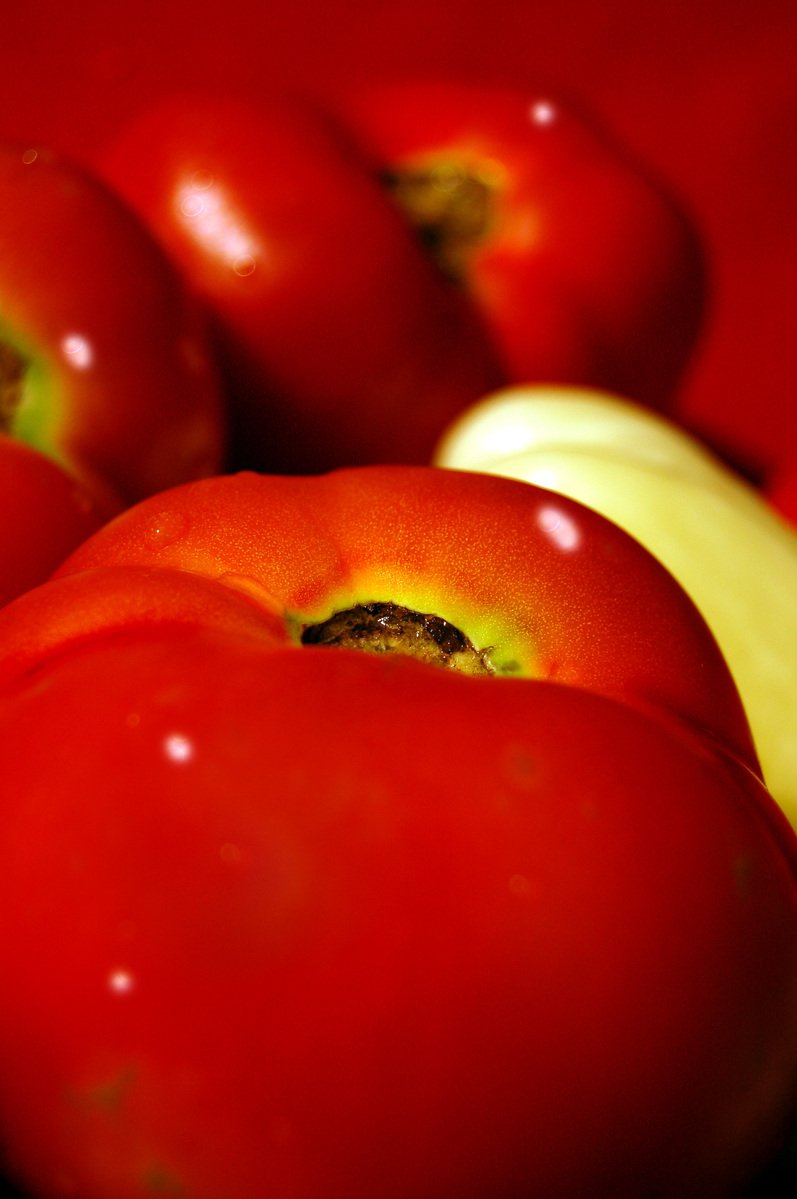 there are three tomatoes in the middle of several red bananas