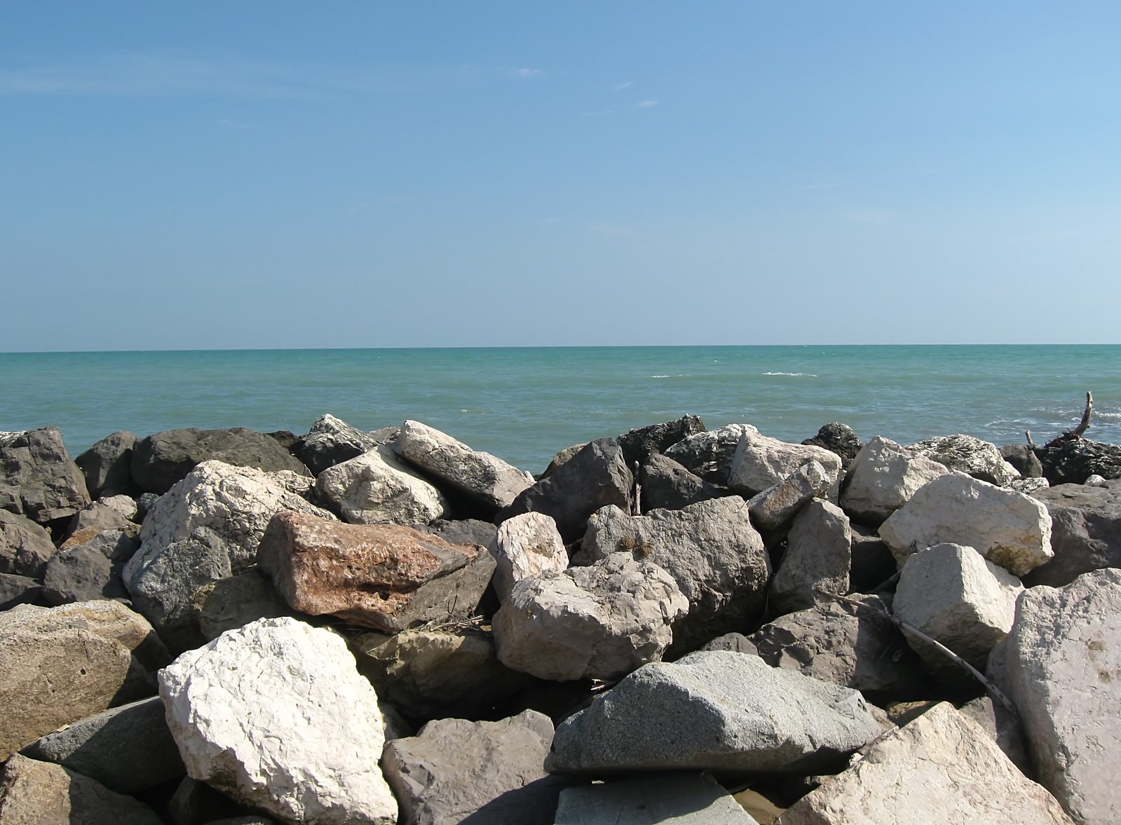 a blue ocean with rocks and two birds standing on it