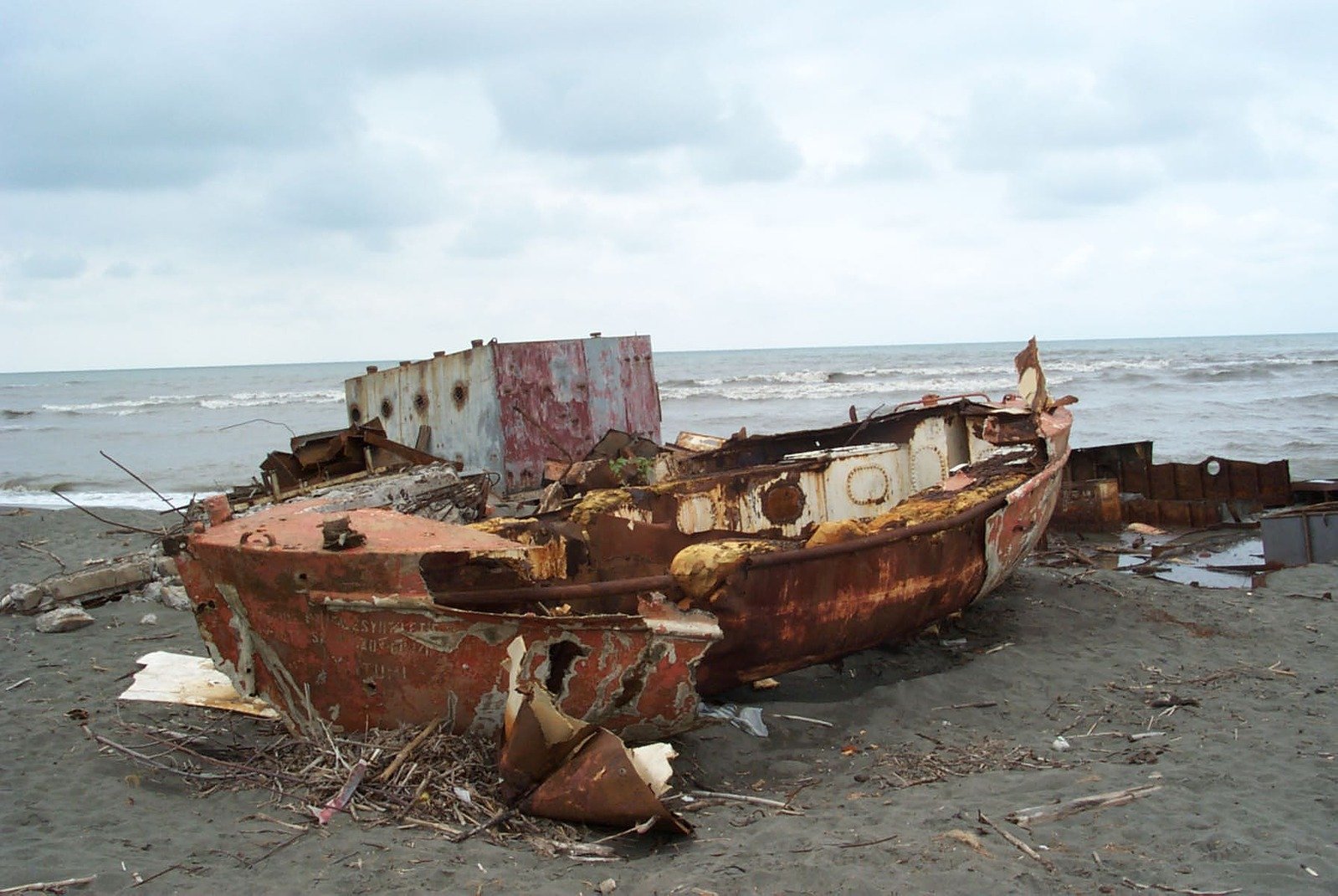 a rusted boat sitting on top of a sandy beach