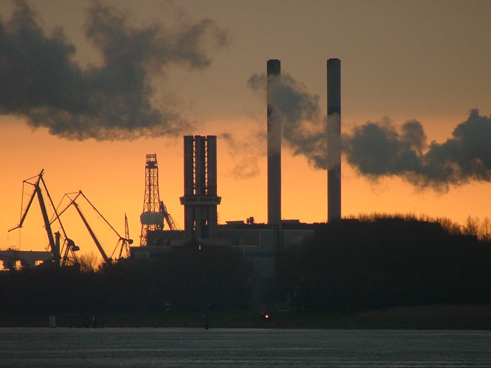 smoke stacks are billowing from the chimneys at sunset