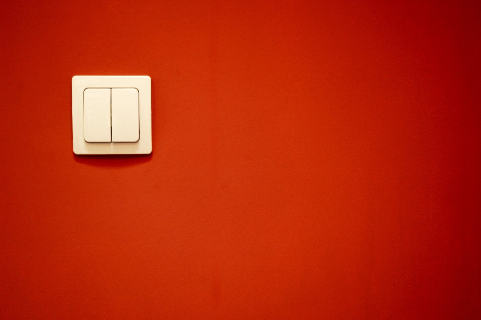 two light switches on a red wall with a white light switch on it