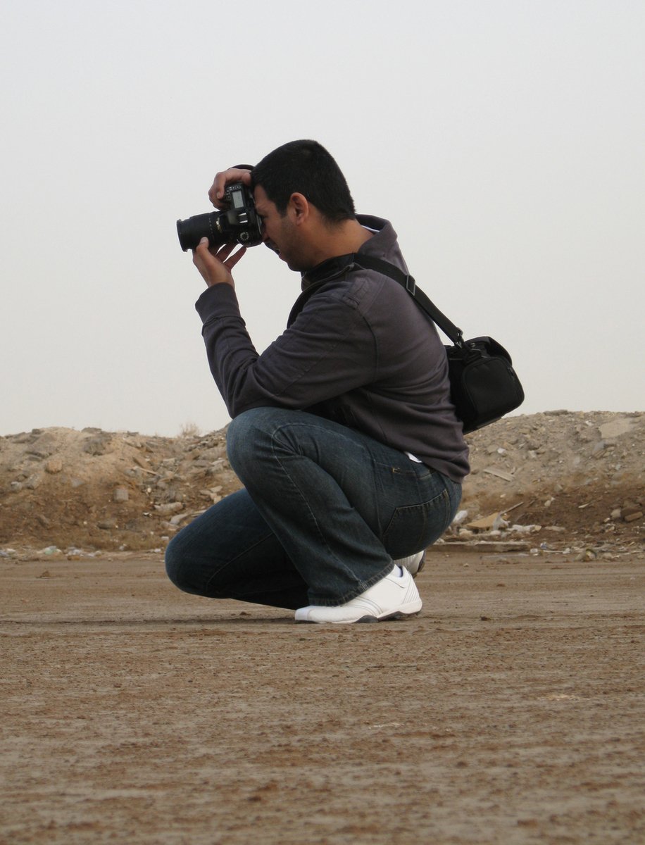 a man kneeling down with a camera to take a po