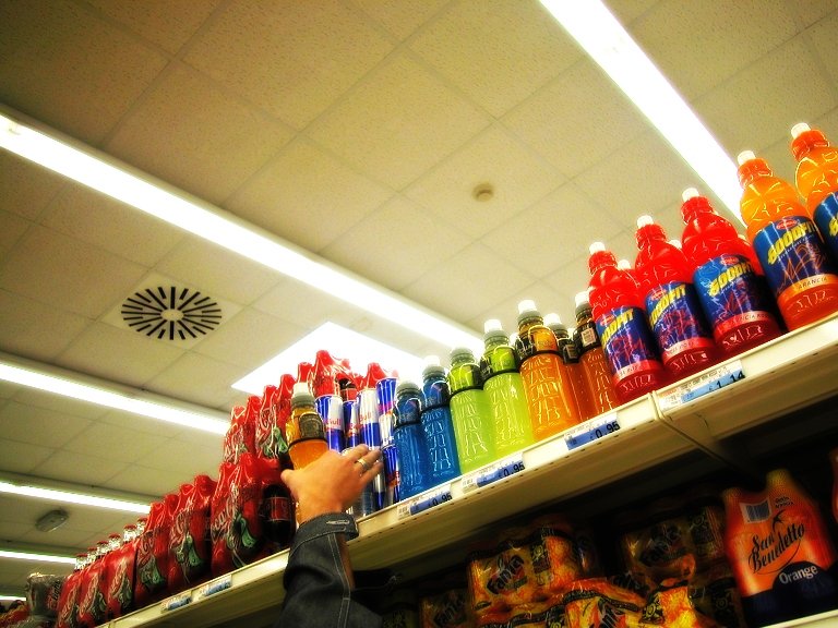 the person is looking at all the soda bottles on display