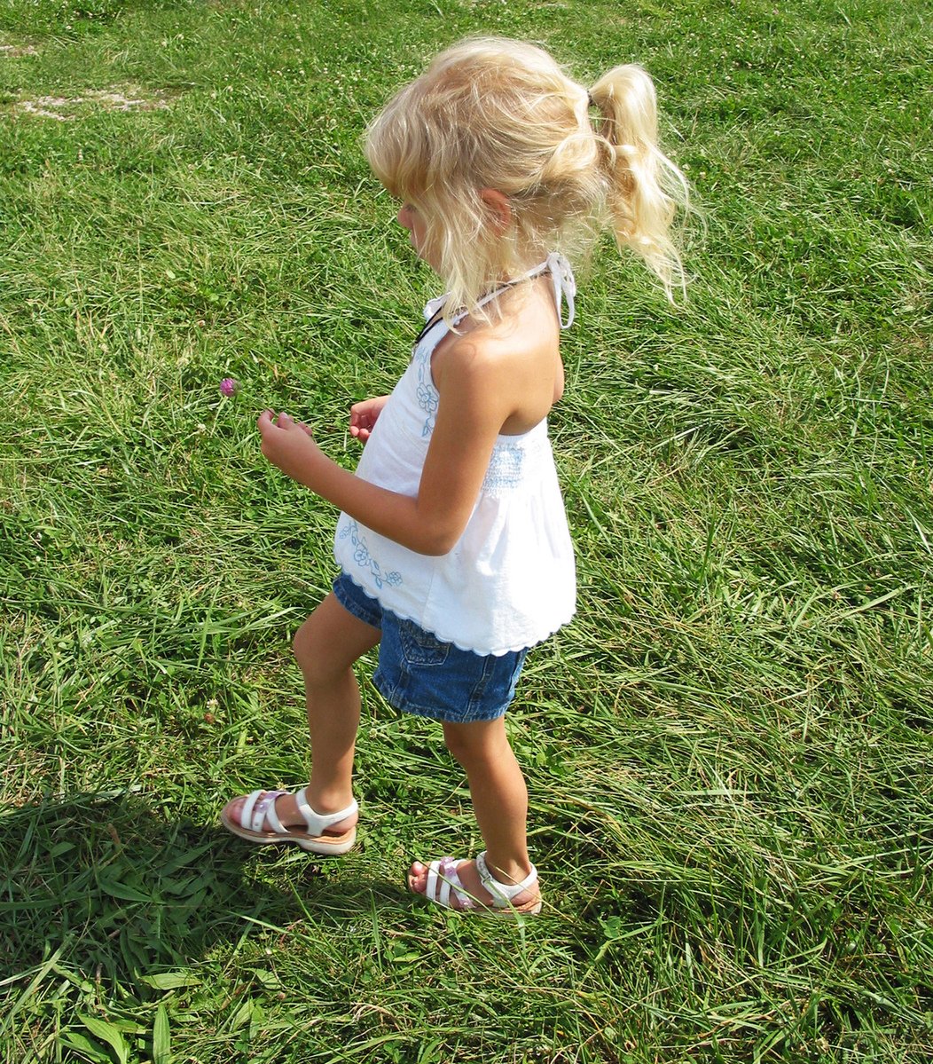 a little girl is in the grass holding a small cell phone
