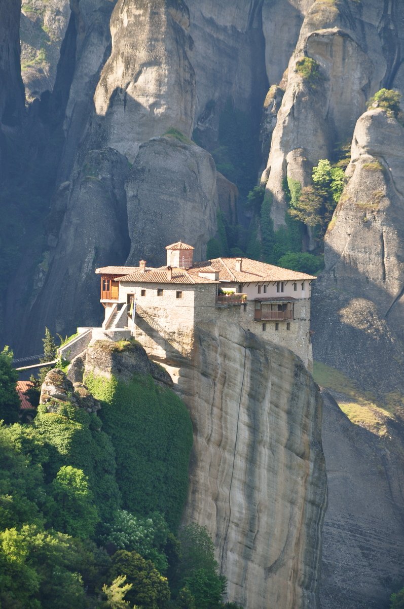 a building on a rocky ledge near the mountains