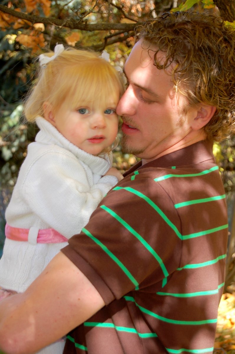 a man holding a child under a tree