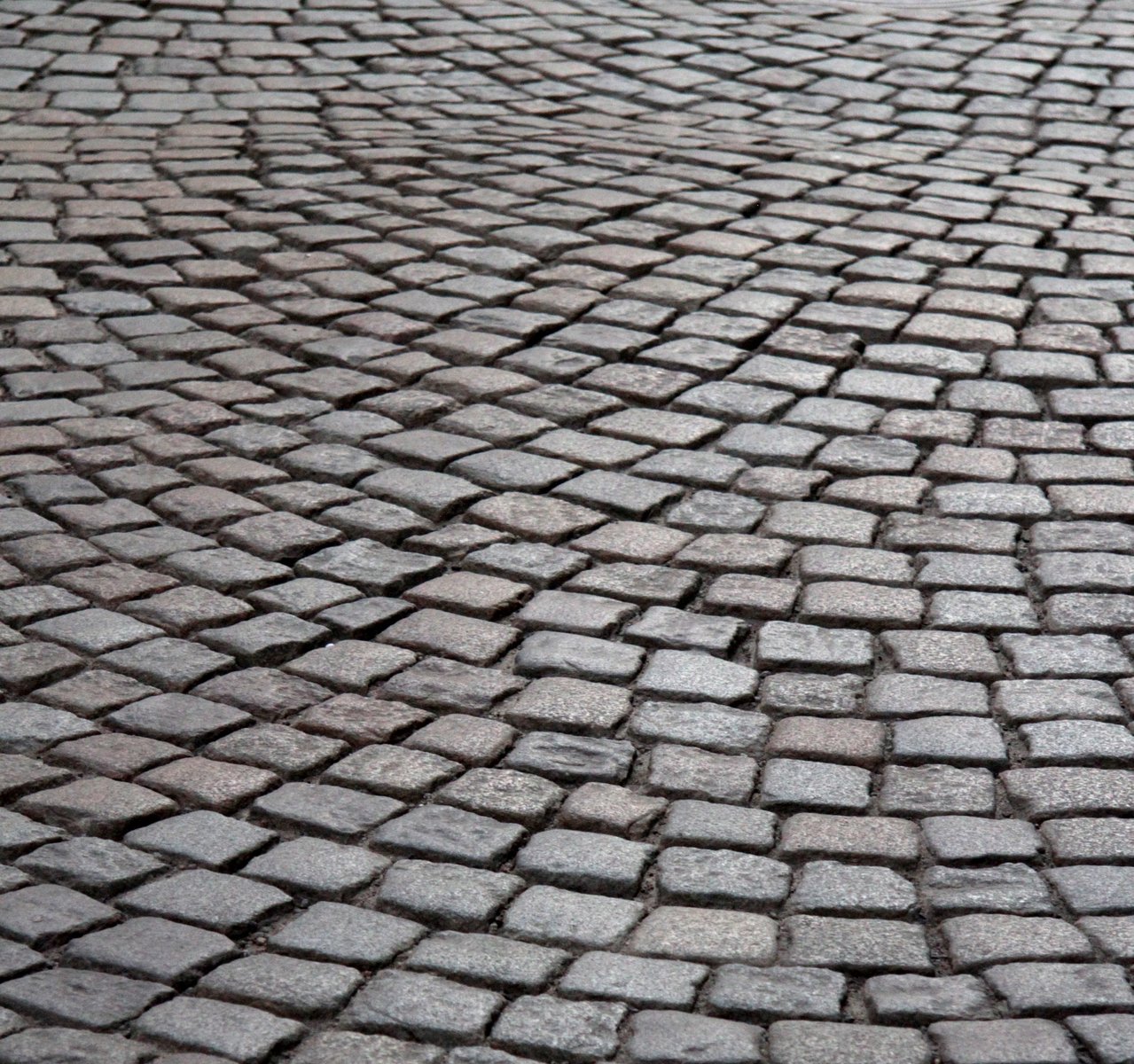 a stop sign that is in the middle of a cobblestone road