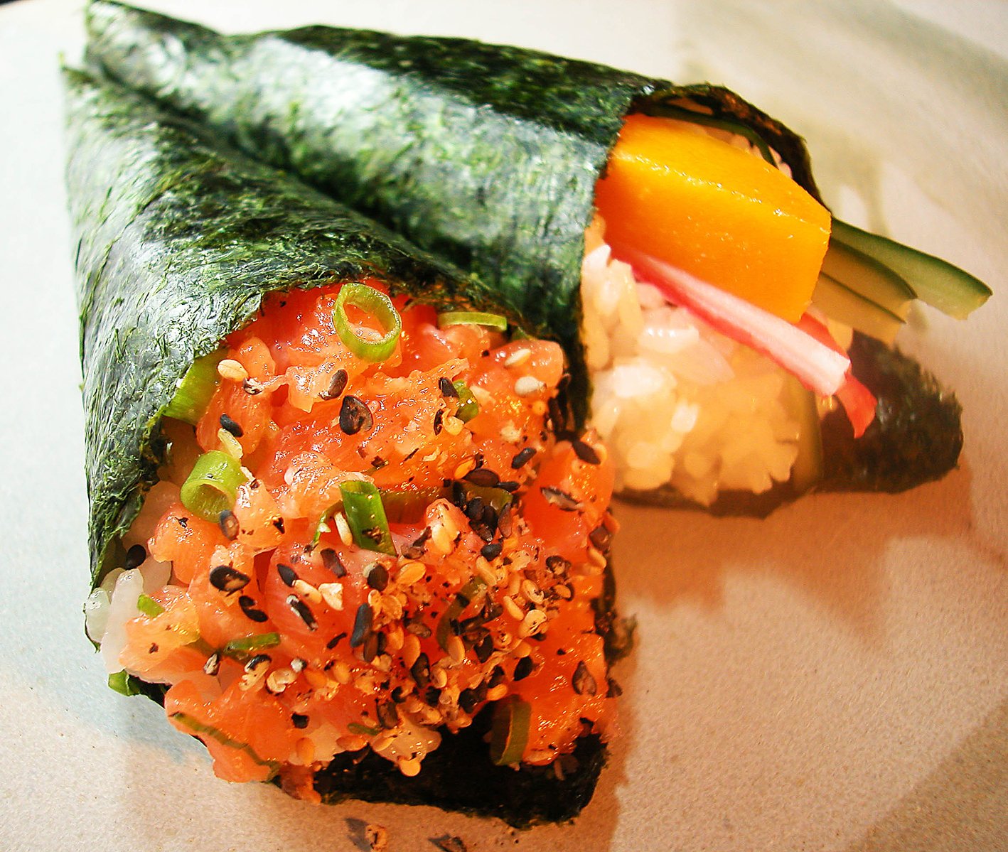 a rolled up sushi with cucumber, carrots and onion on a plate