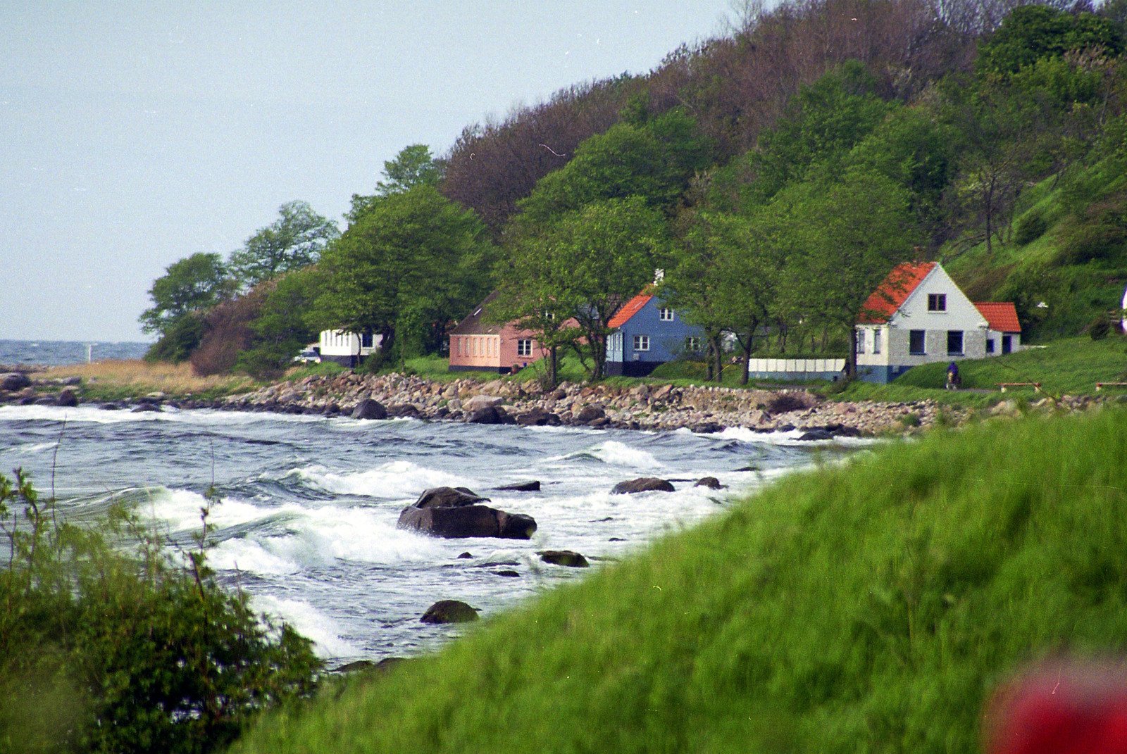 an ocean beach near some houses and cliffs