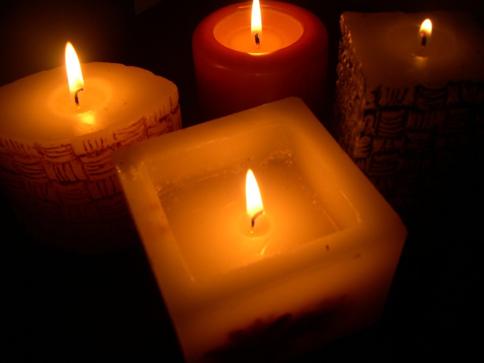 three lit candles are in a row and one is empty