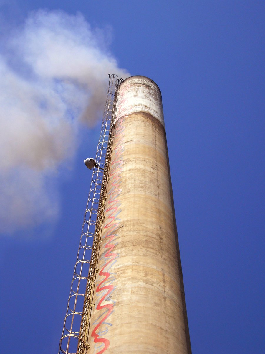 a tall smoke stack with a cloudy blue sky in the background