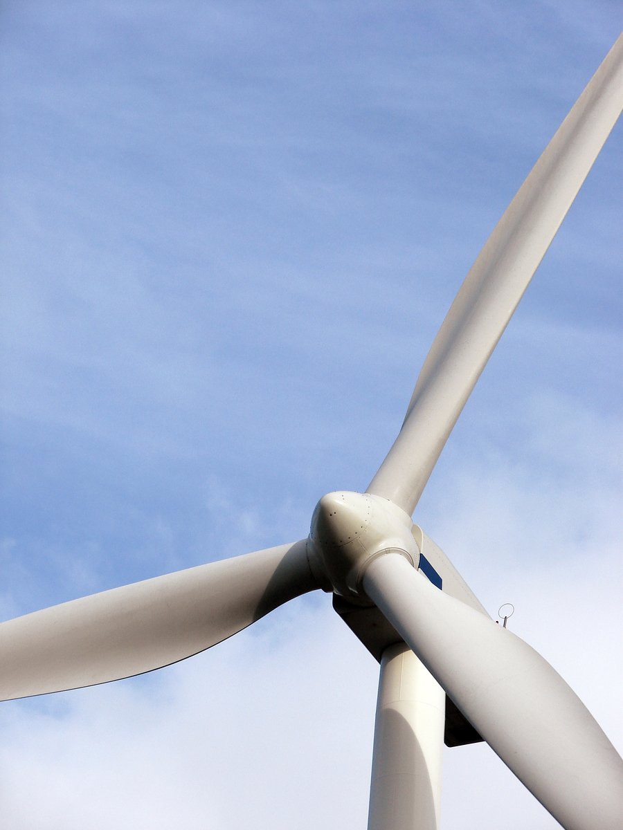 a wind turbine with four blades is pictured from below