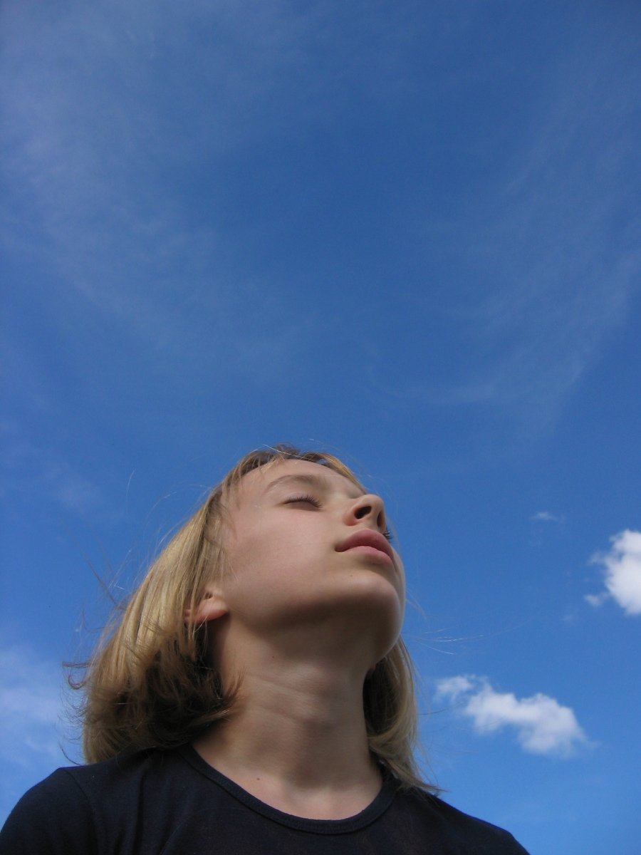 a woman looks up in the air with a bright sun above her