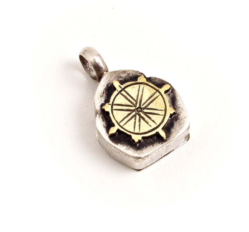 a silver and gold charm with a compass