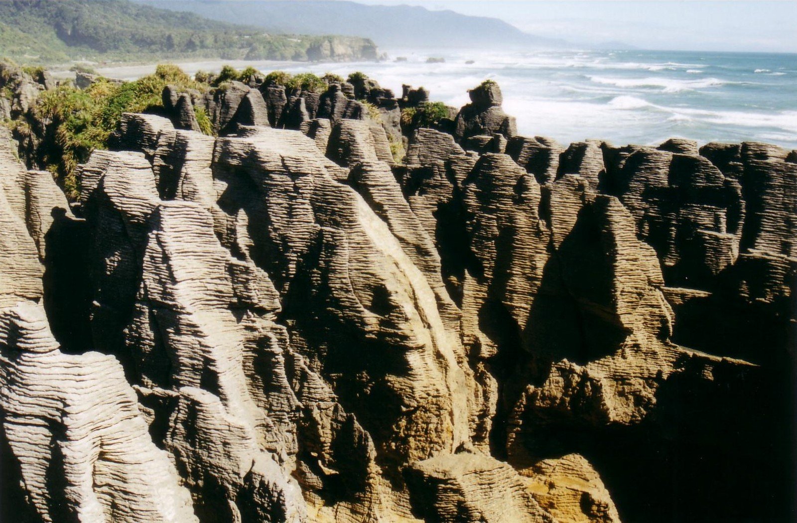 rock formations and the ocean and mountains on a sunny day
