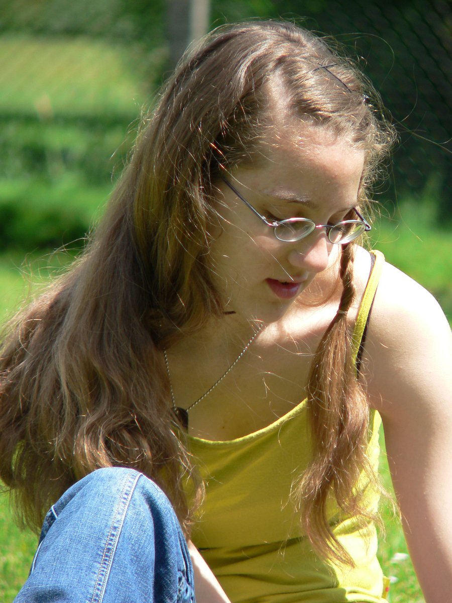 the woman is sitting in the grass reading soing