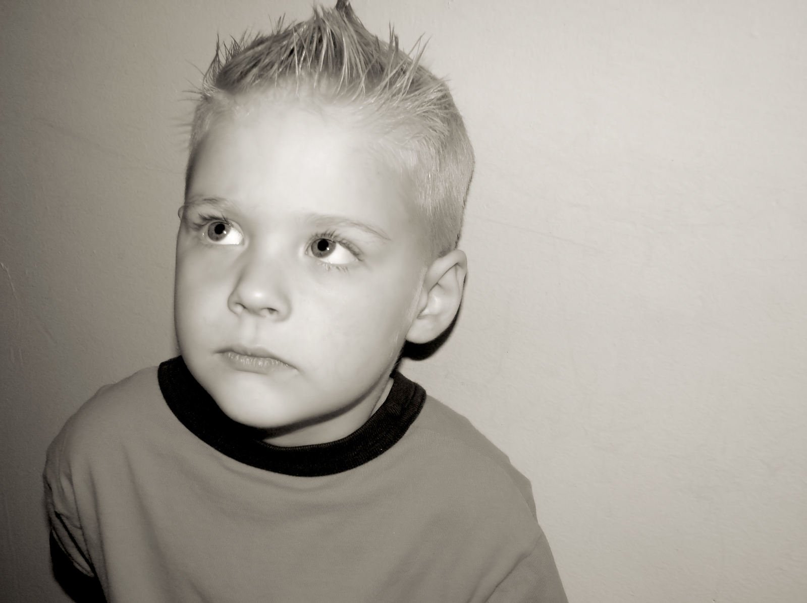 a boy wearing a brown shirt is looking into the distance