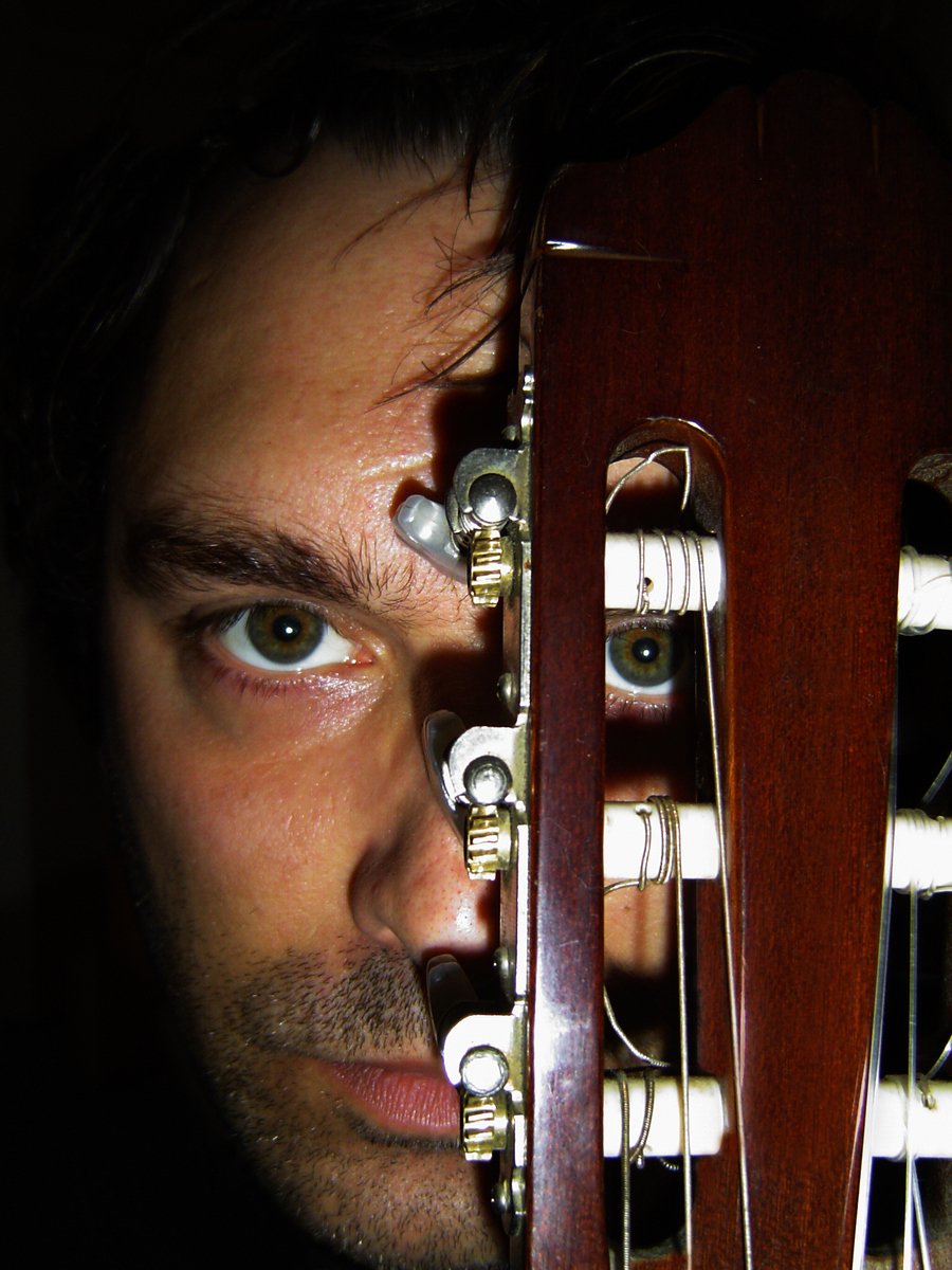 a man with blue eyes holds a guitar over his face