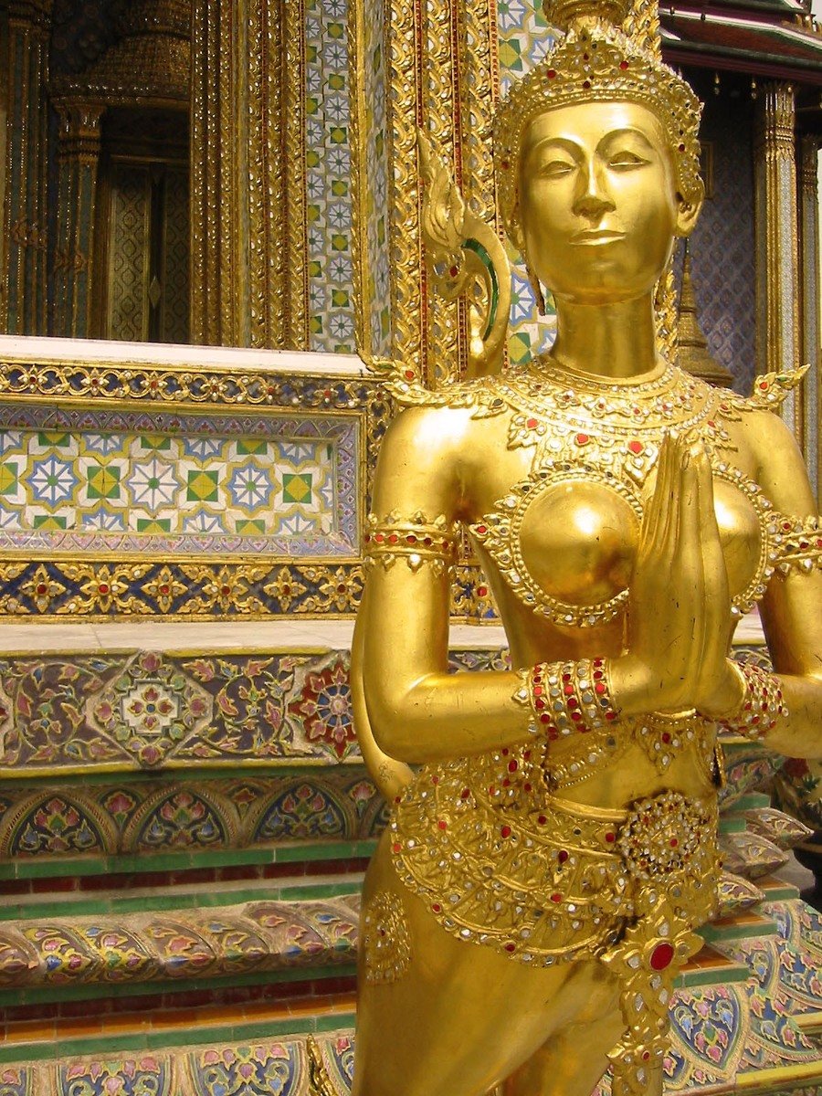 the golden statue is in front of the large gold sculpture