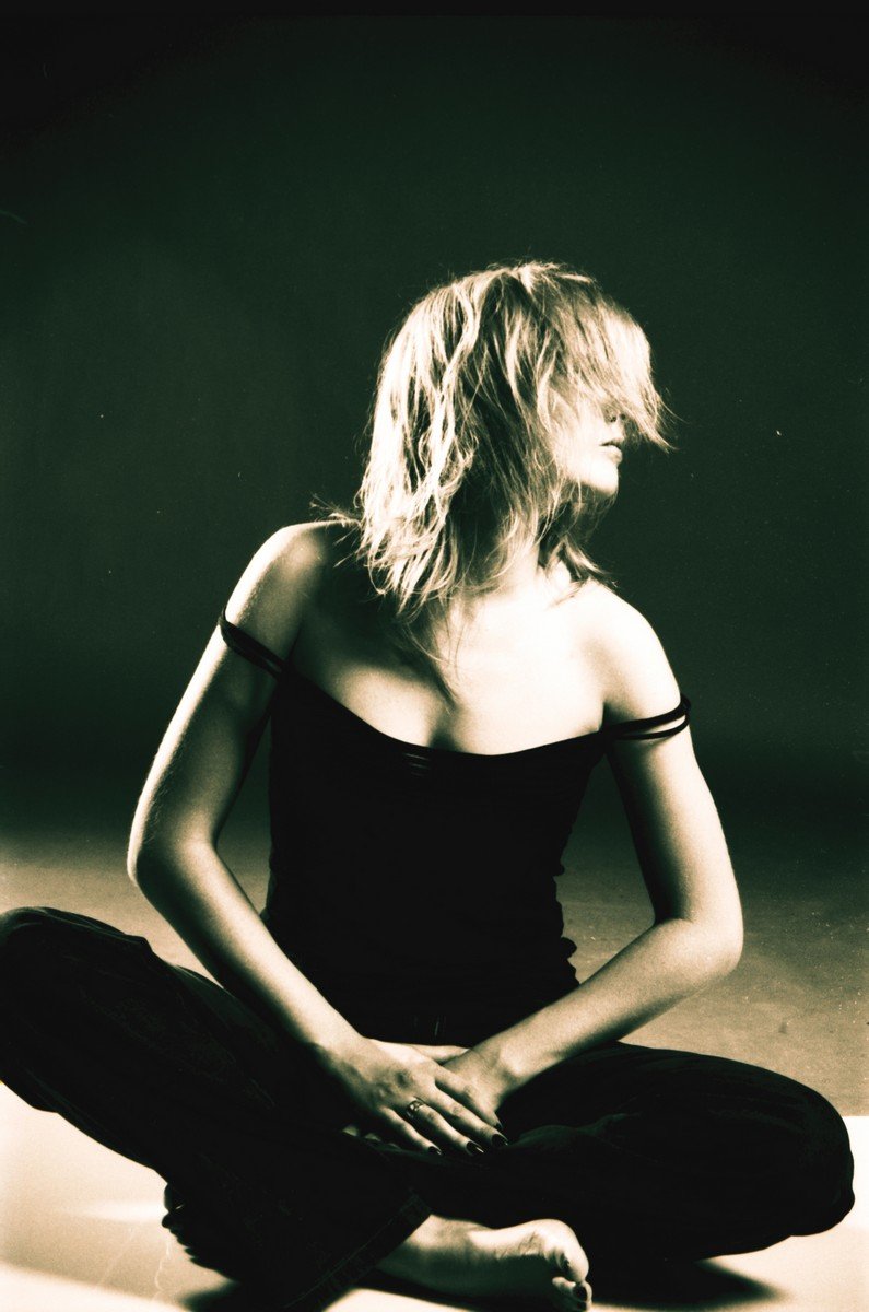 a woman in a black top sitting in the middle of a floor