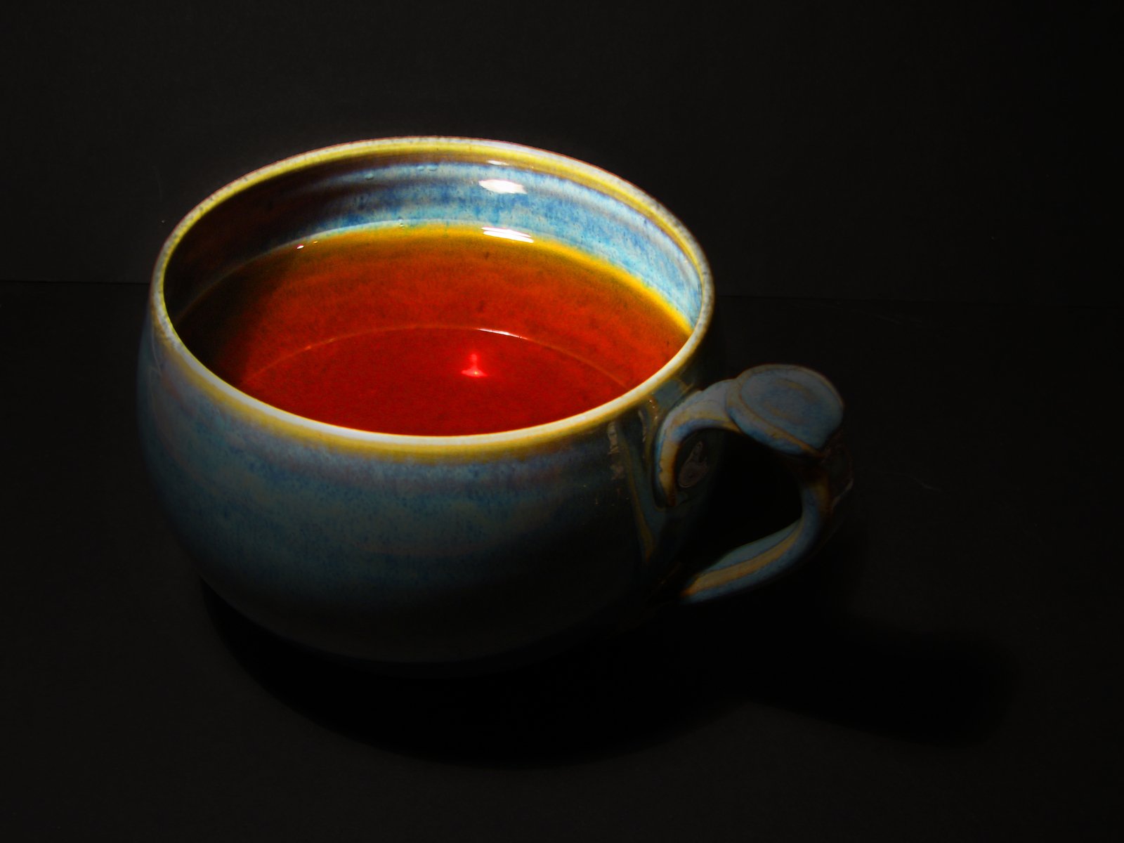 a coffee cup with red and orange liquid sitting on top