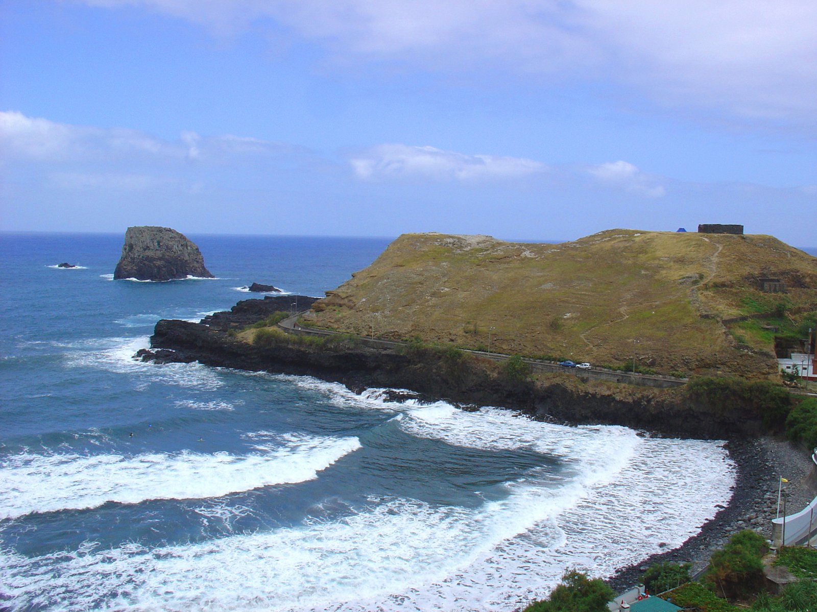 the view from above the water looking at a hill next to the ocean