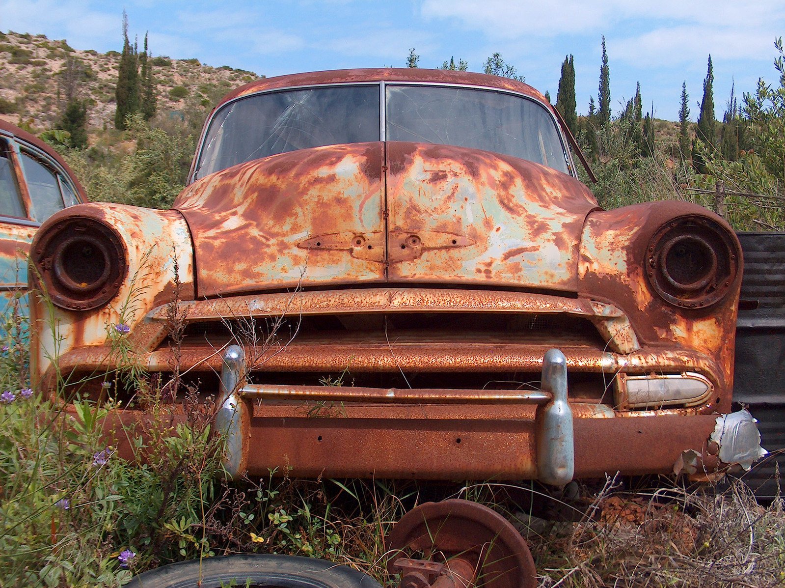 an old rusty truck in the middle of a field with grass and weeds