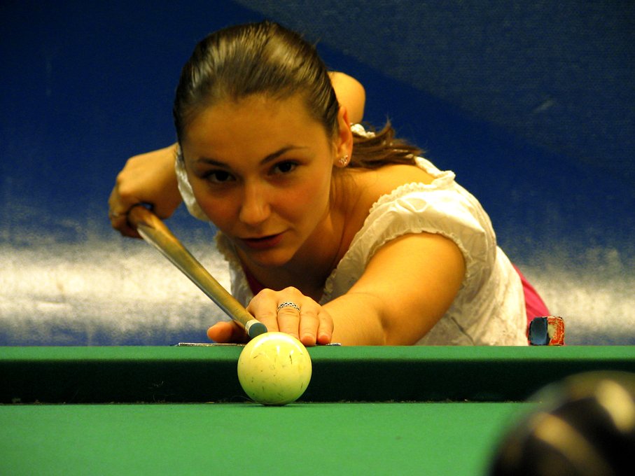 a woman playing pool and leaning over to hit the ball