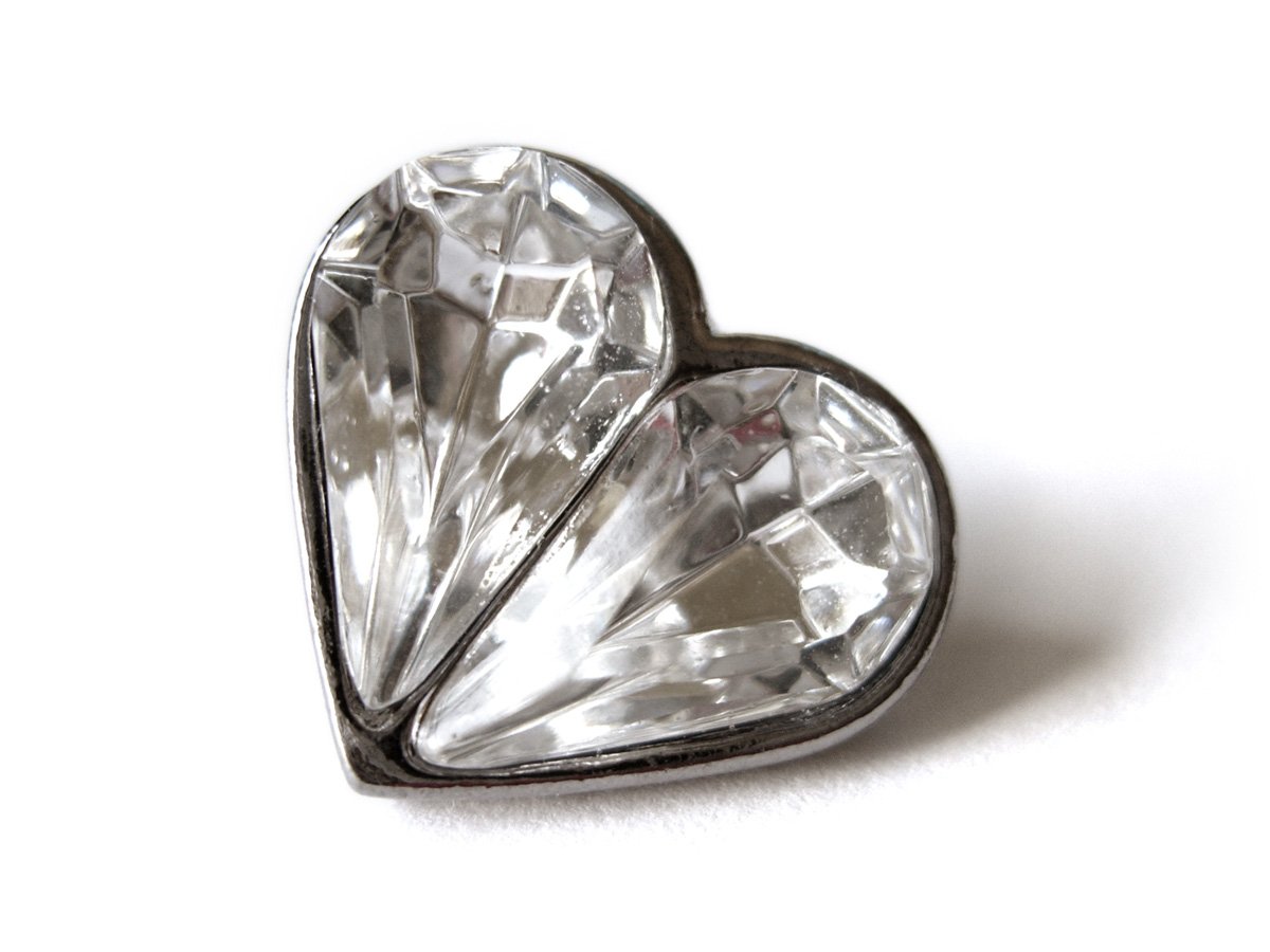 a heart shaped diamond ring on a white surface