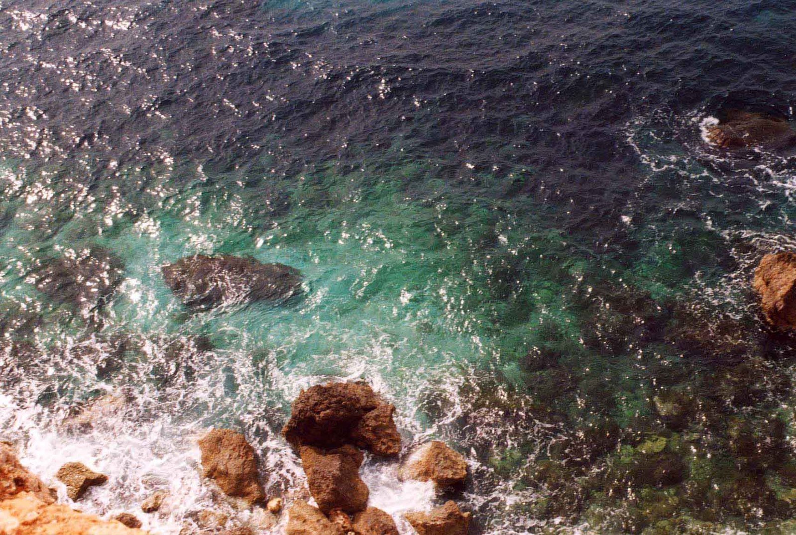 the ocean has blue green water and some brown rocks