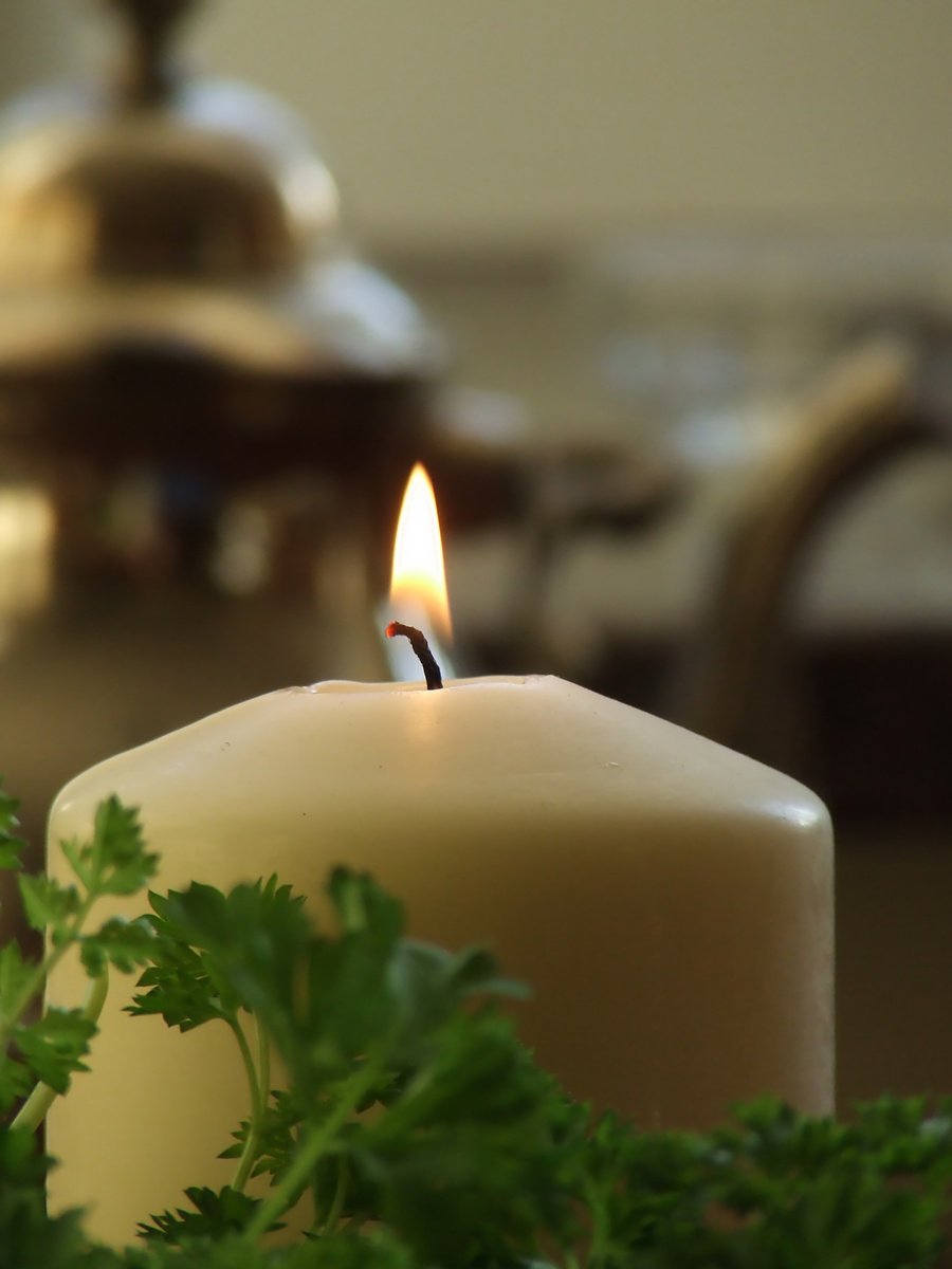 a candle lit on a table near some flowers