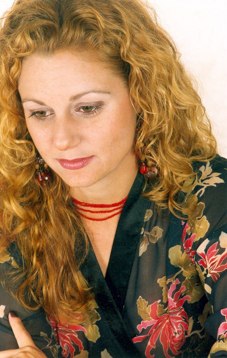 a woman wearing a black top with floral print holding soing in her right hand