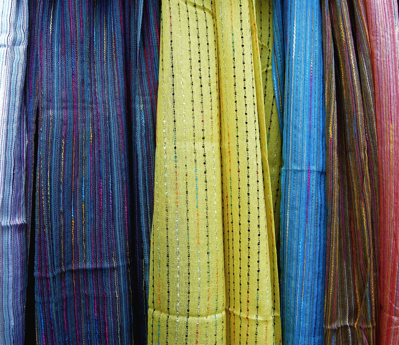 there is many colorful scarves hanging from hooks