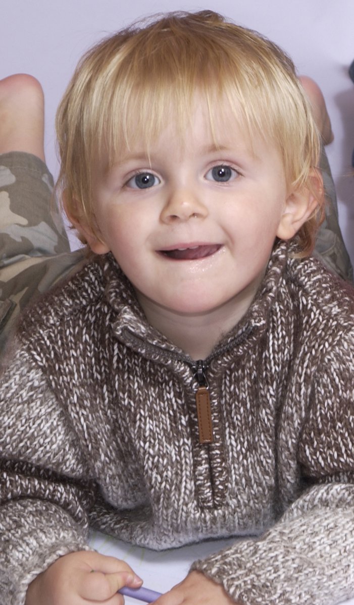 a boy lying down in pajamas smiles