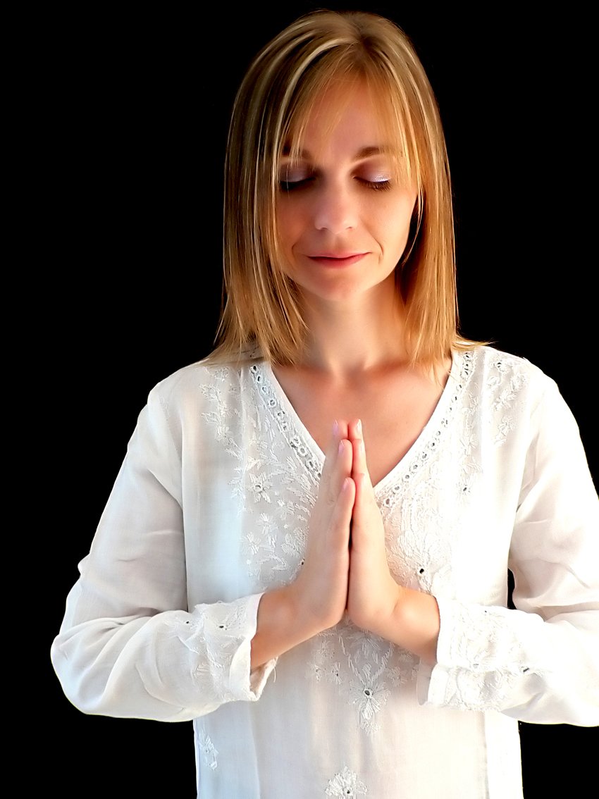a woman standing with her hands folded in prayer