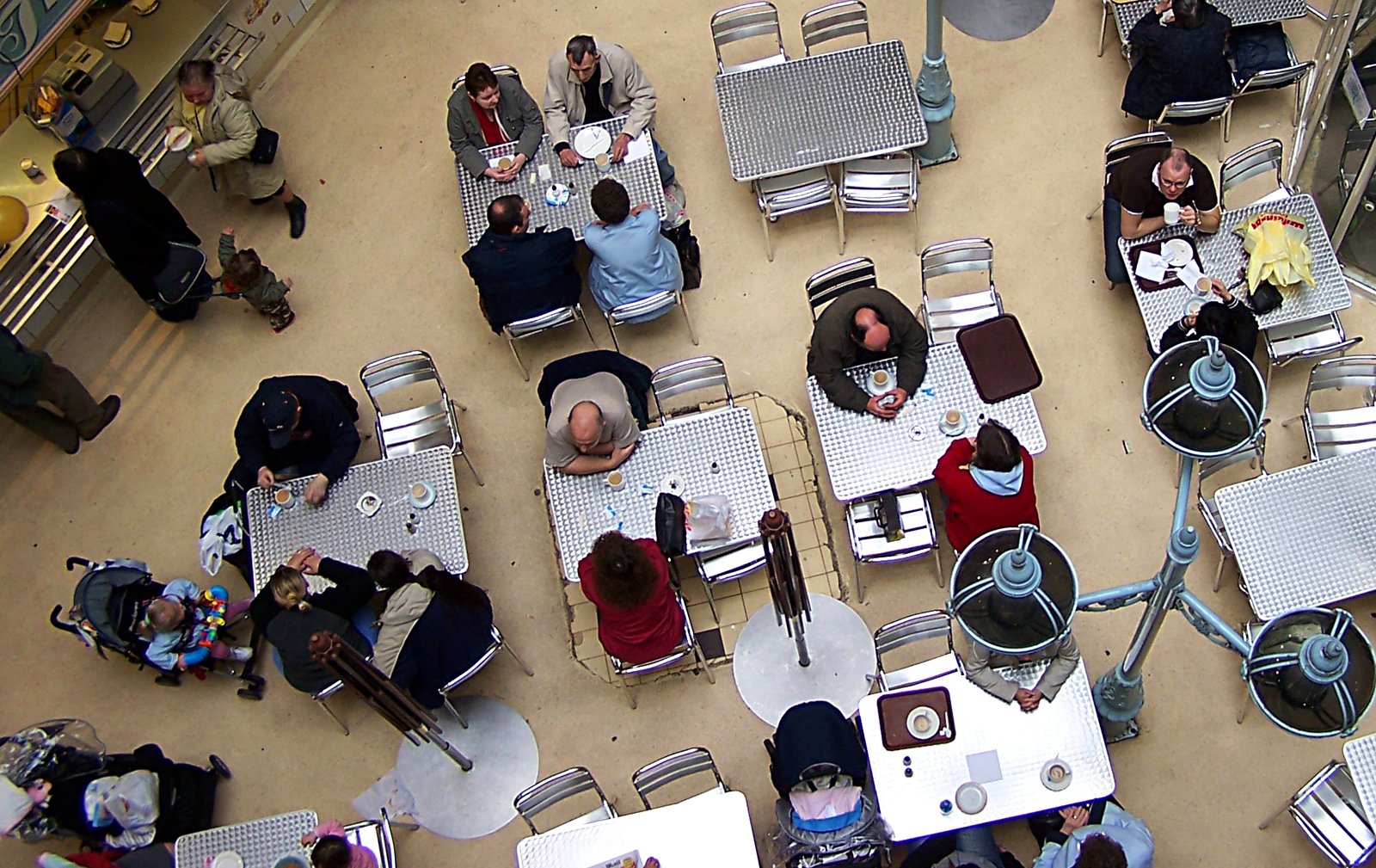 several people sitting in small tables and chairs next to each other