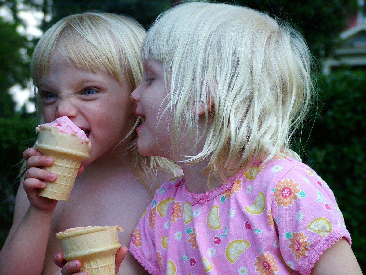 two small children sitting eating ice cream together