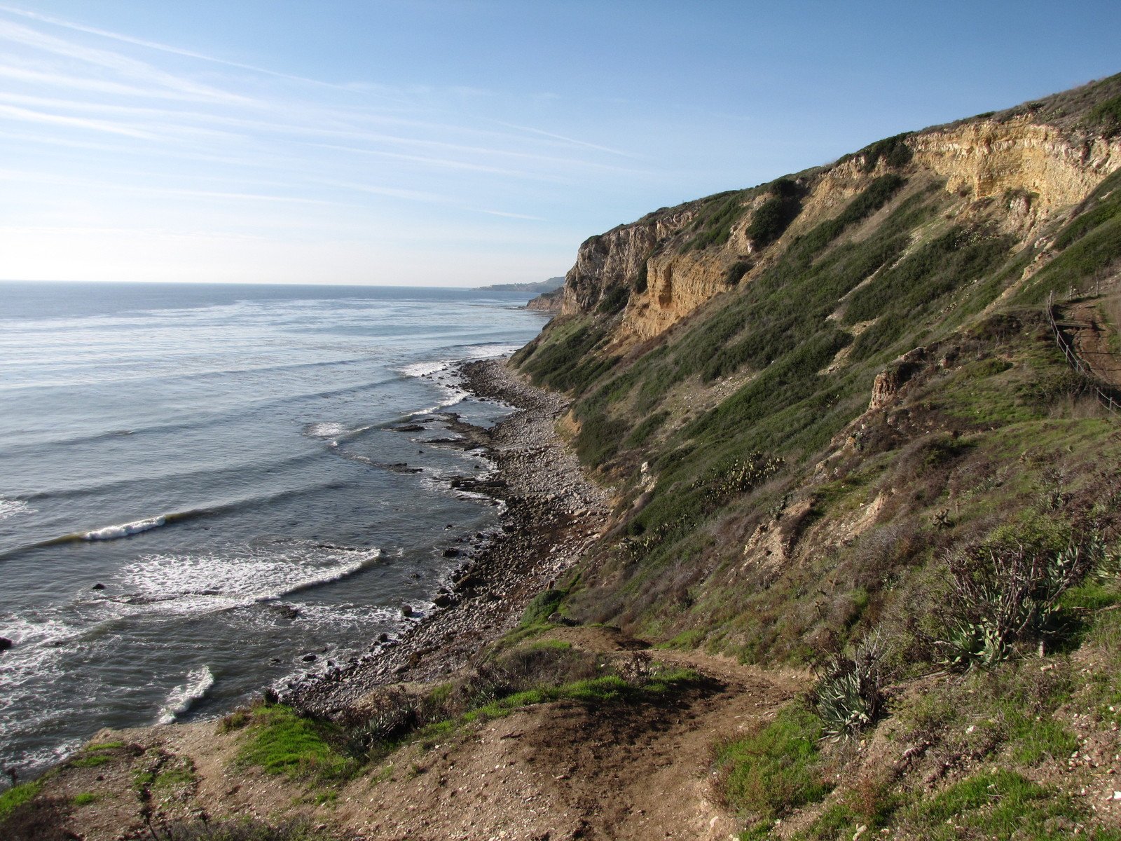 a dirt path along the ocean with water