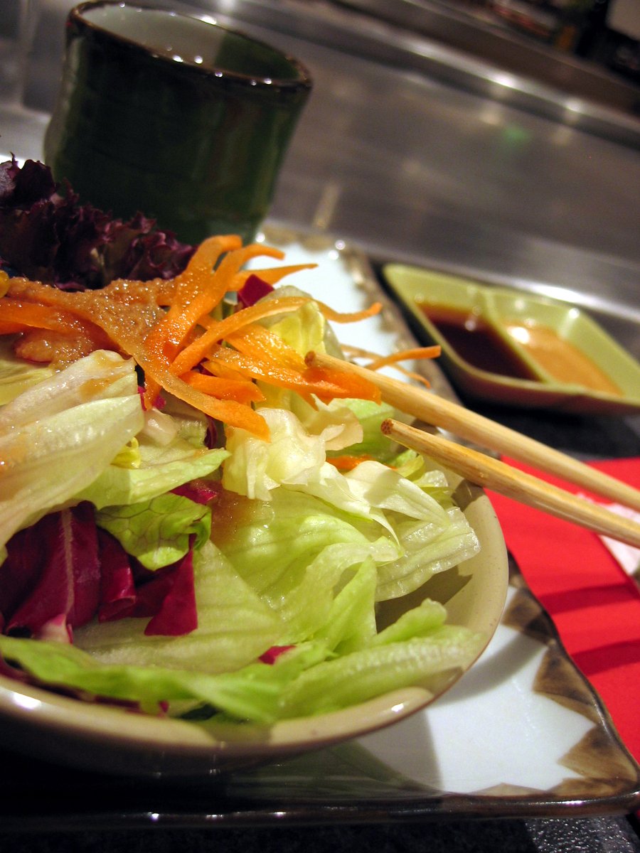 a bowl with food next to chopsticks on a plate