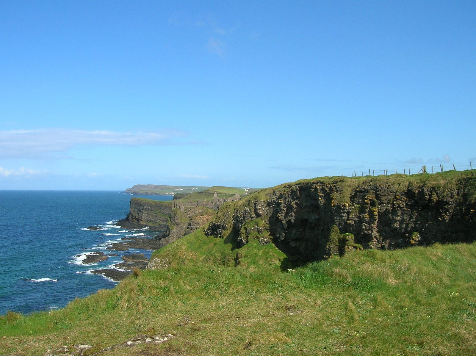 a bird flies near a rock cliff at the edge of the ocean