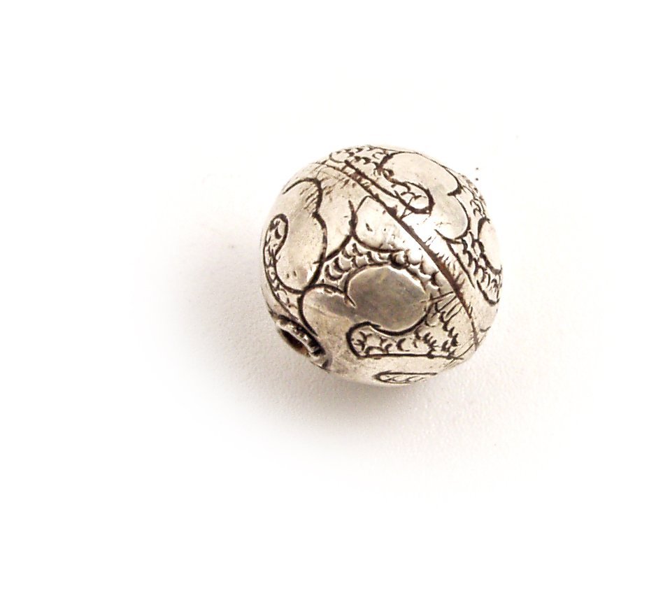 a round silver object with an intricate pattern on it